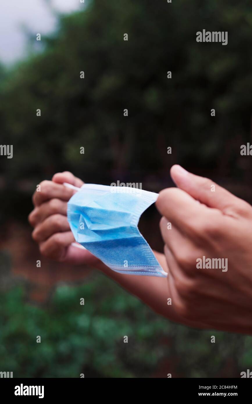 primo piano di un giovane contadino che sta per indossare una maschera chirurgica in un frutteto biologico Foto Stock