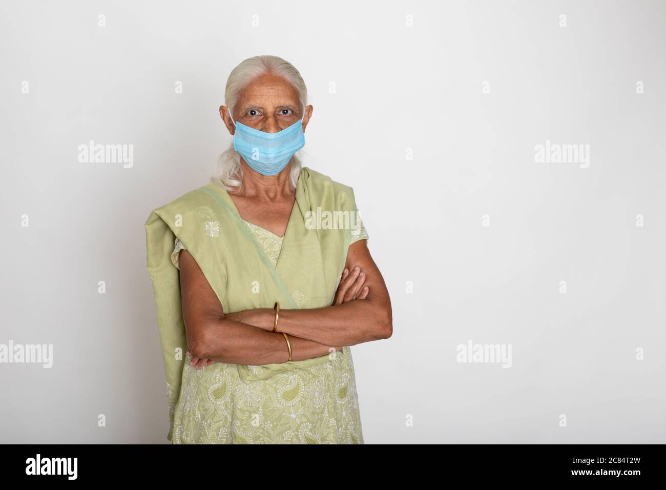 Donna indiana matura che indossa maschera di protezione Covid, nonna indiana che leviga con le braccia incrociate Foto Stock