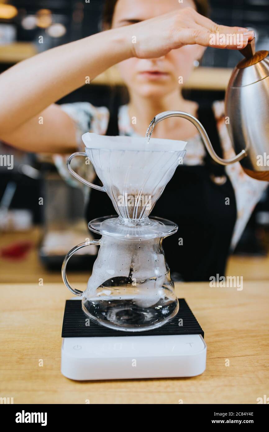 Preparazione del caffè con un filtro a forma di imbuto su un recipiente di vetro Foto Stock