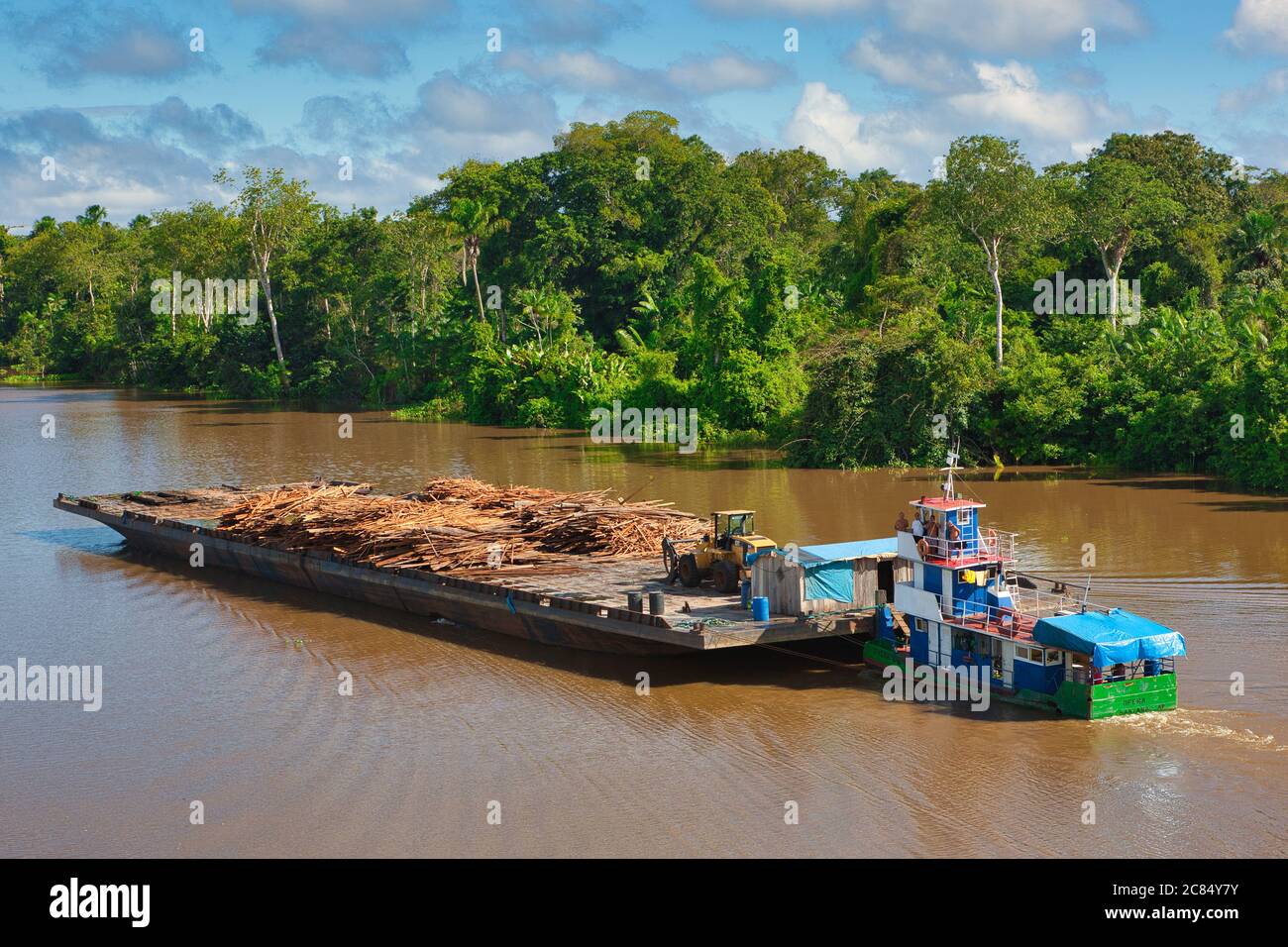Un tugboat che spinge una grande chiatta caricata di legname a monte sul fiume Amazon con uno sfondo di foresta pluviale oltre, nello Stato di Para, Brasile Foto Stock