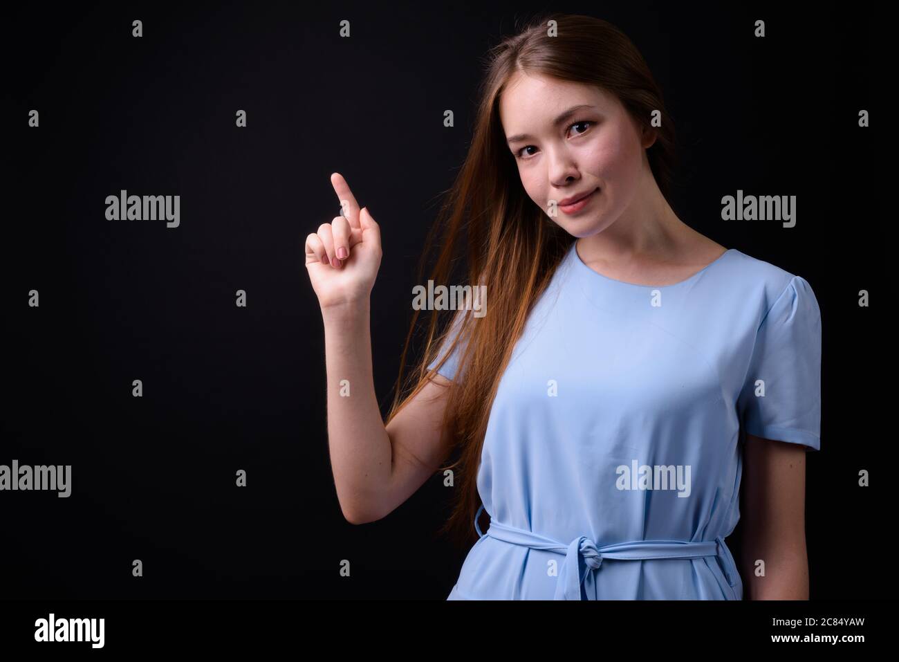 Giovane bella donna con lunghi capelli marroni su sfondo nero Foto Stock