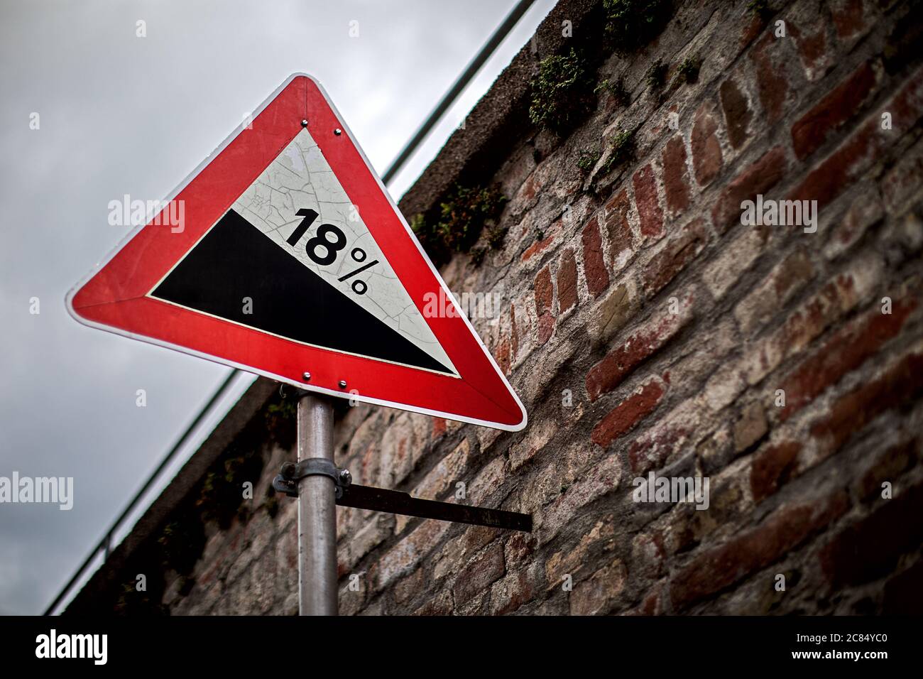 segnale stradale monted su un vecchio muro di mattoni avvertimento di un pendio Foto Stock