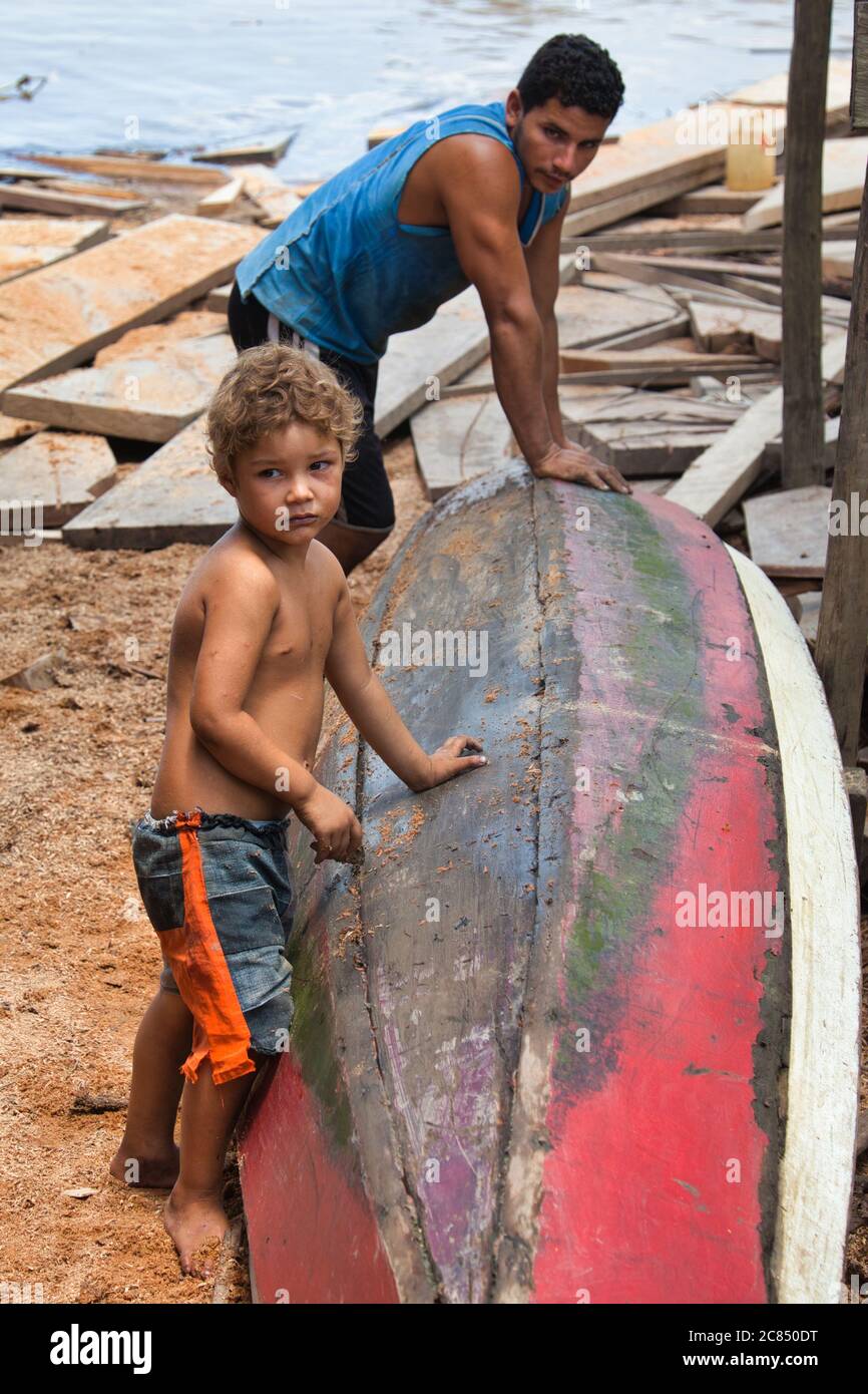 Padre e figlio insieme con una canoa dall'acqua su cui stanno appoggiando, a Macapa, Stato di Amapa, Brasile Foto Stock