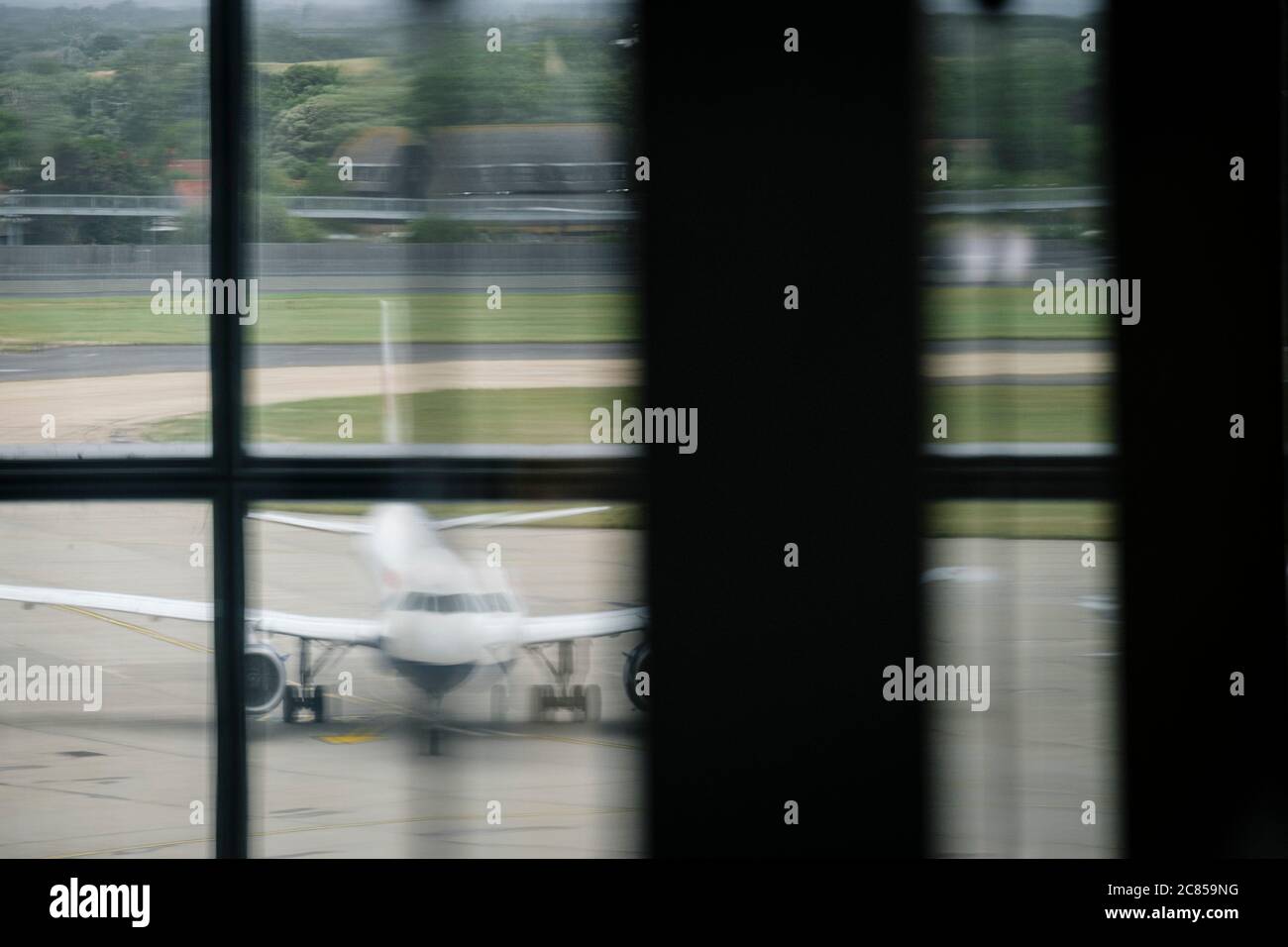 Un jet-Aircraft parcheggiato sul cemento in un aeroporto visto tirare una finestra dall'edificio della sala partenze. Foto Stock