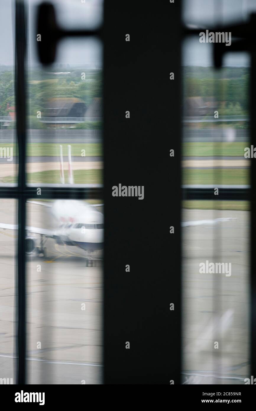 Un jet-Aircraft parcheggiato sul cemento in un aeroporto visto tirare una finestra dall'edificio della sala partenze. Foto Stock