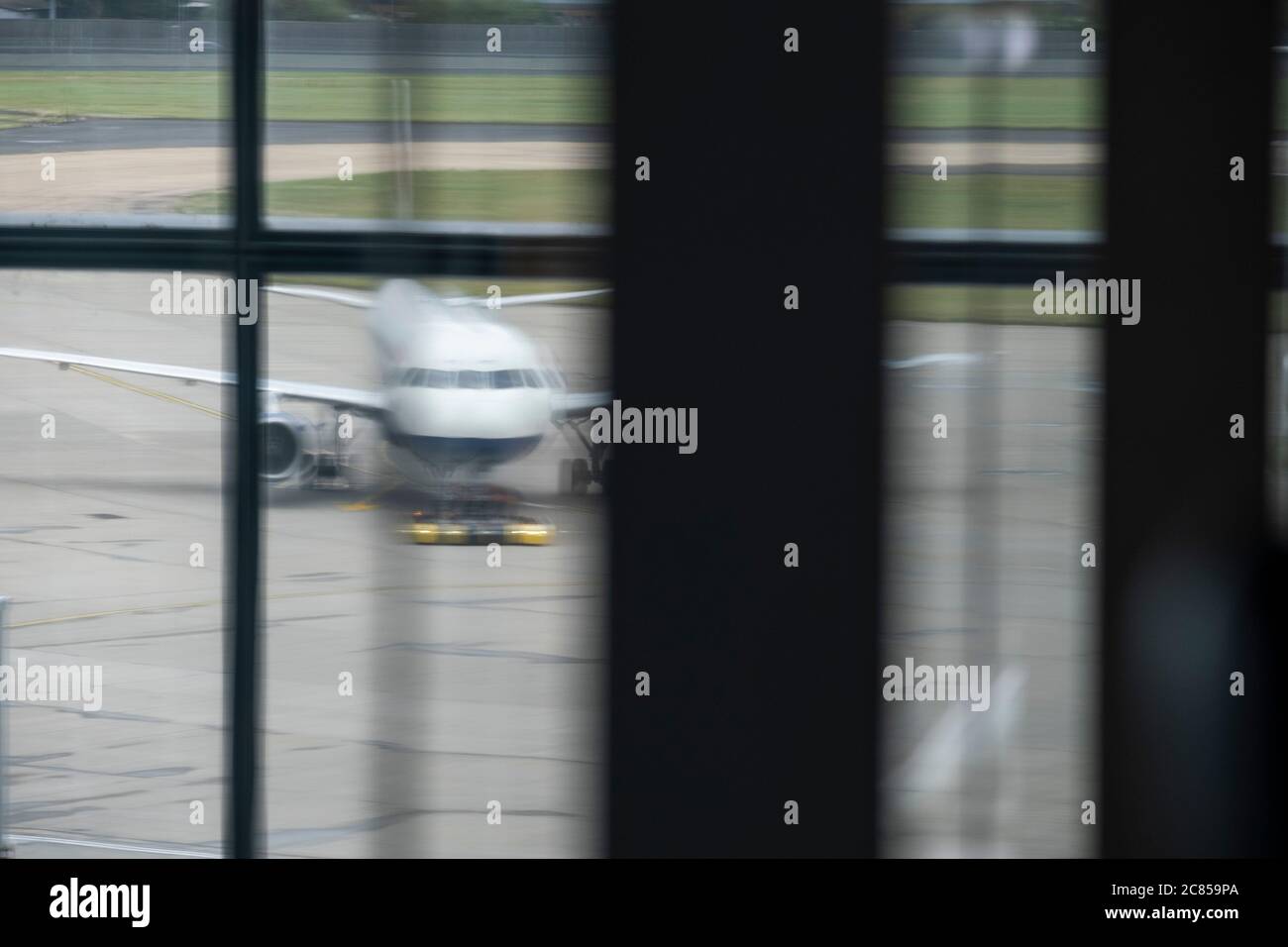 Un jet-Aircraft parcheggiato sul cemento in un aeroporto visto tirare una finestra dall'edificio della sala partenze. Foto Stock