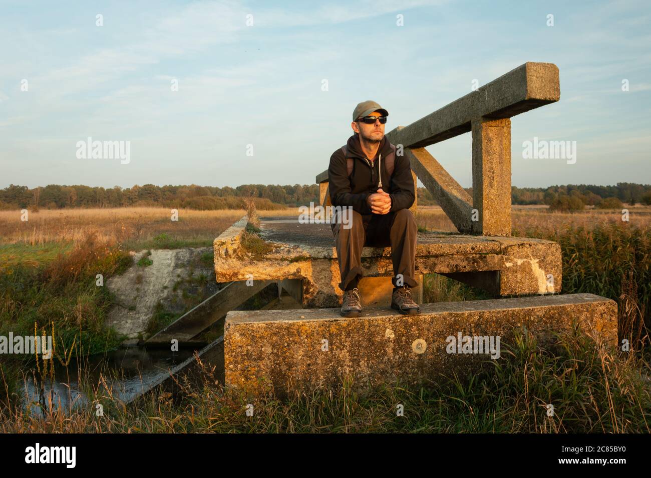 Un uomo seduto su un vecchio ponte, vista serale Foto Stock