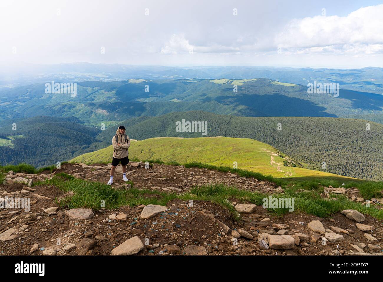 Alpinista con zaino sulla roccia che gode di vista sulle grandi montagne, stile di vita escursionistico, uomo in cima Foto Stock