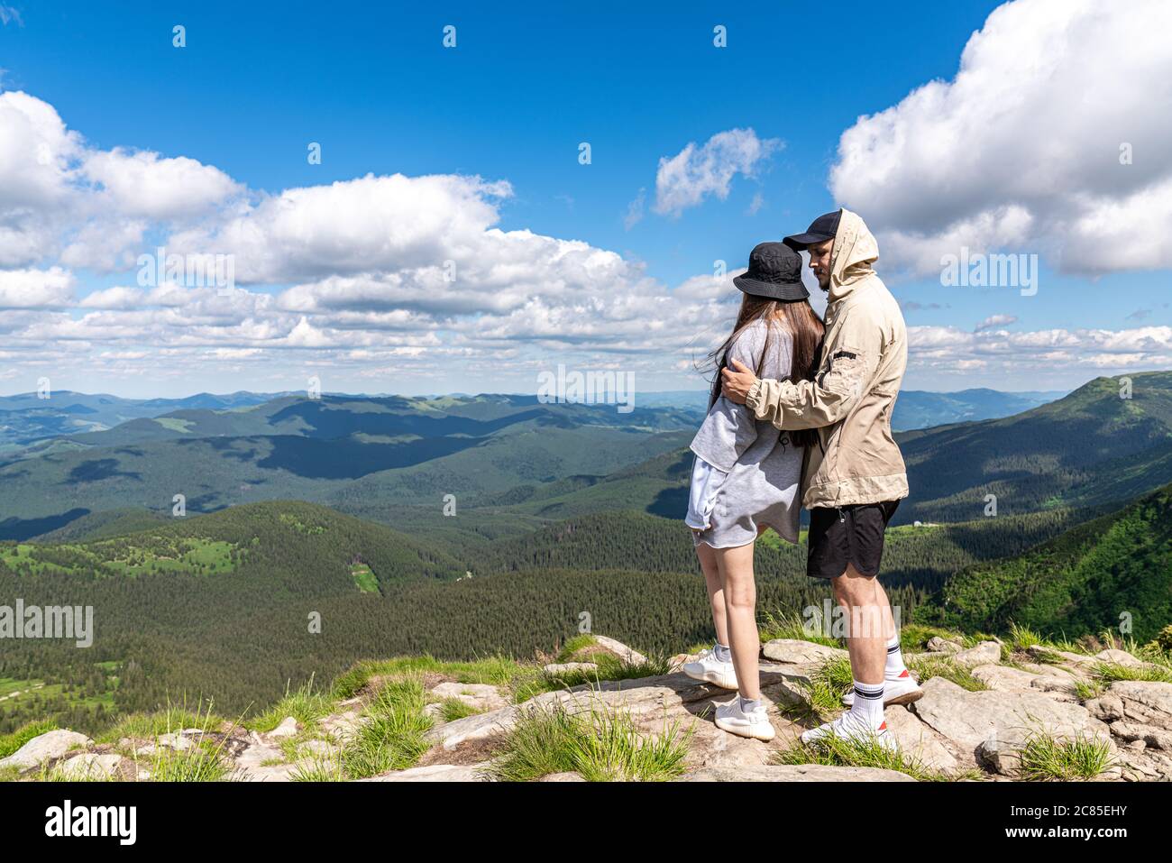 Vista posteriore di coppie escursionisti in piedi sulla cima della montagna e godendo la vista durante il giorno Foto Stock