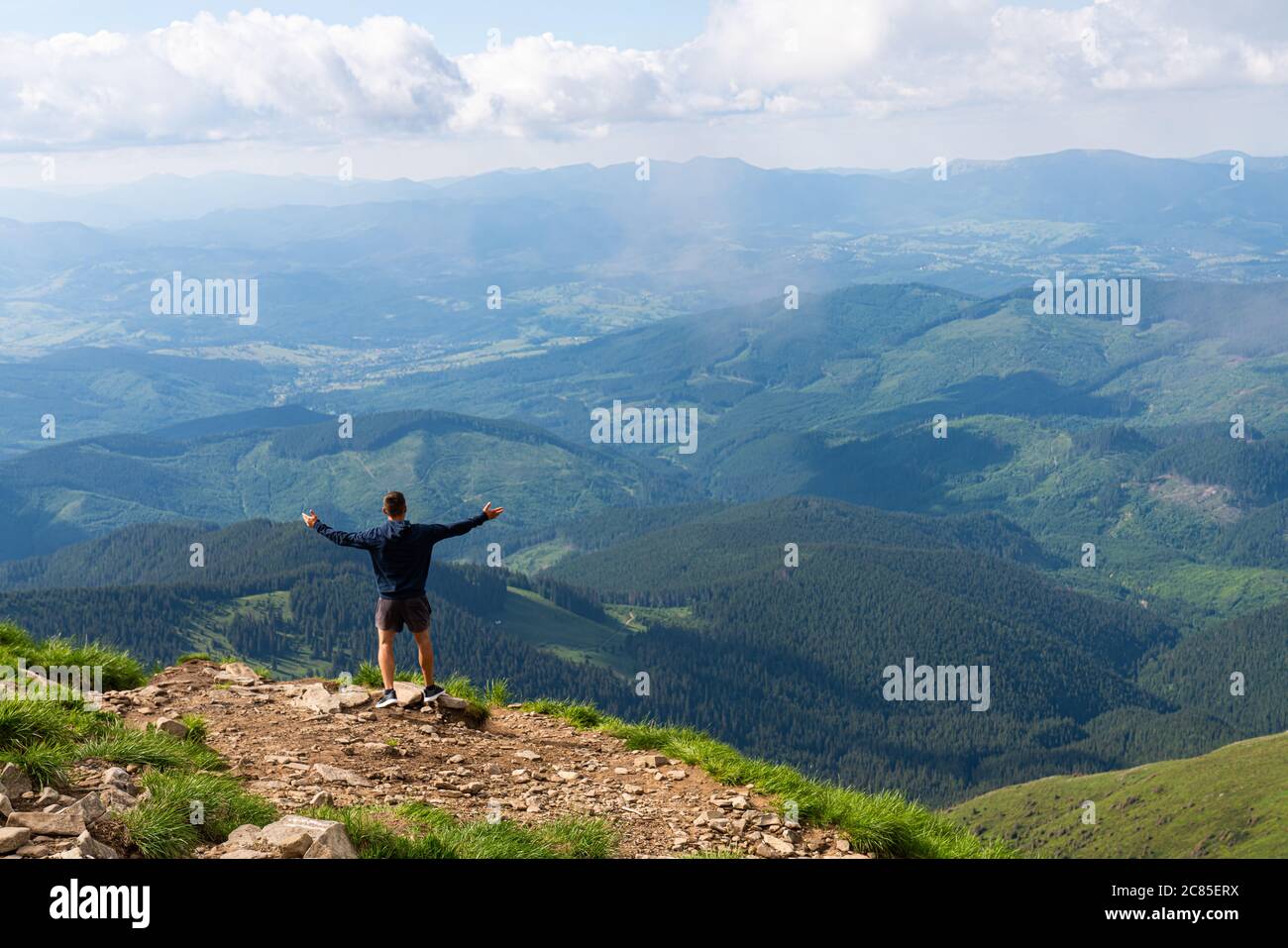 Escursionista in silhouette si erge sulla roccia nelle splendide montagne con le mani che si alzano in un paesaggio incredibile Foto Stock