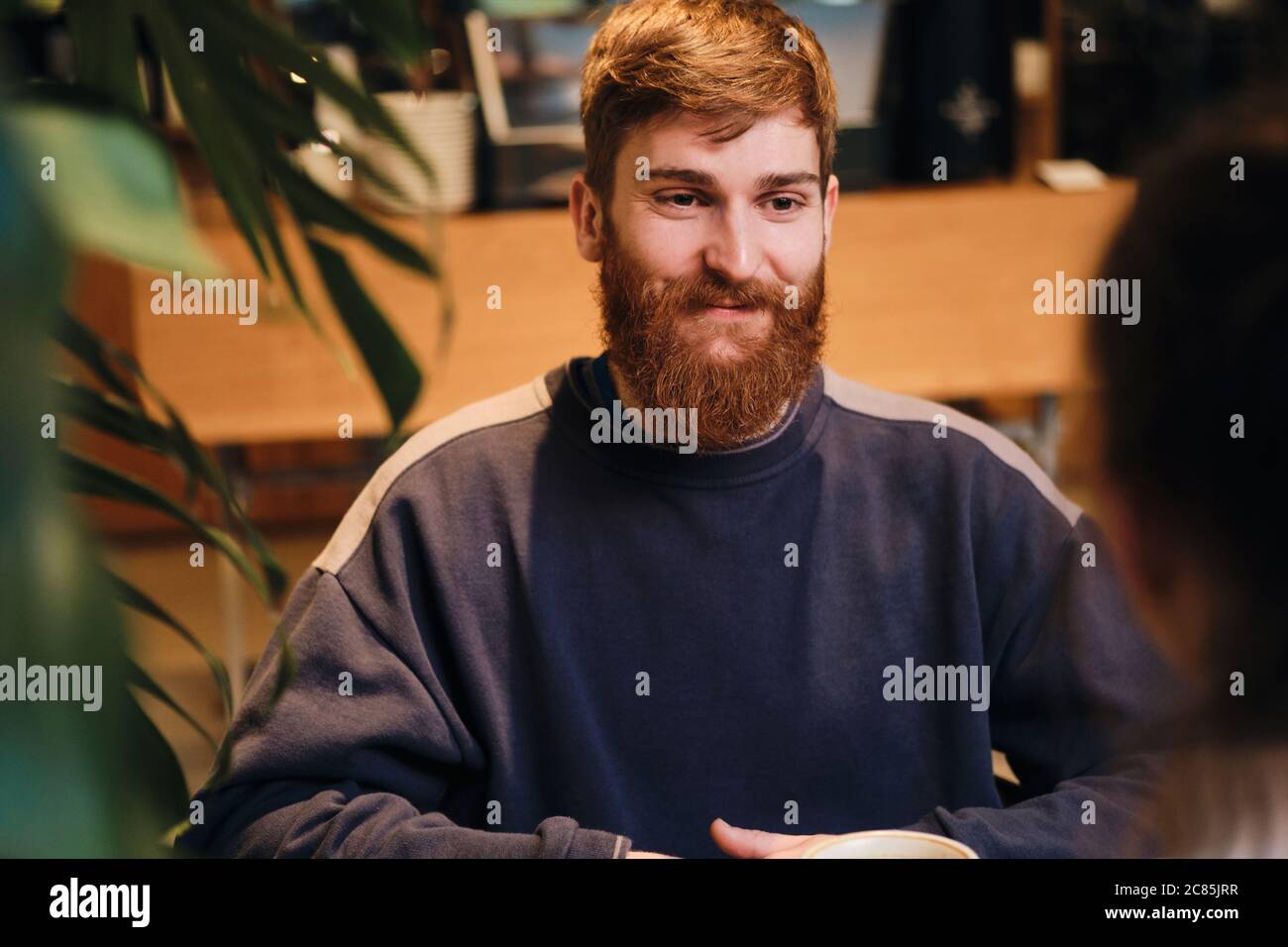 Giovane uomo allegro che guarda felice via per la riunione in un accogliente cafe Foto Stock