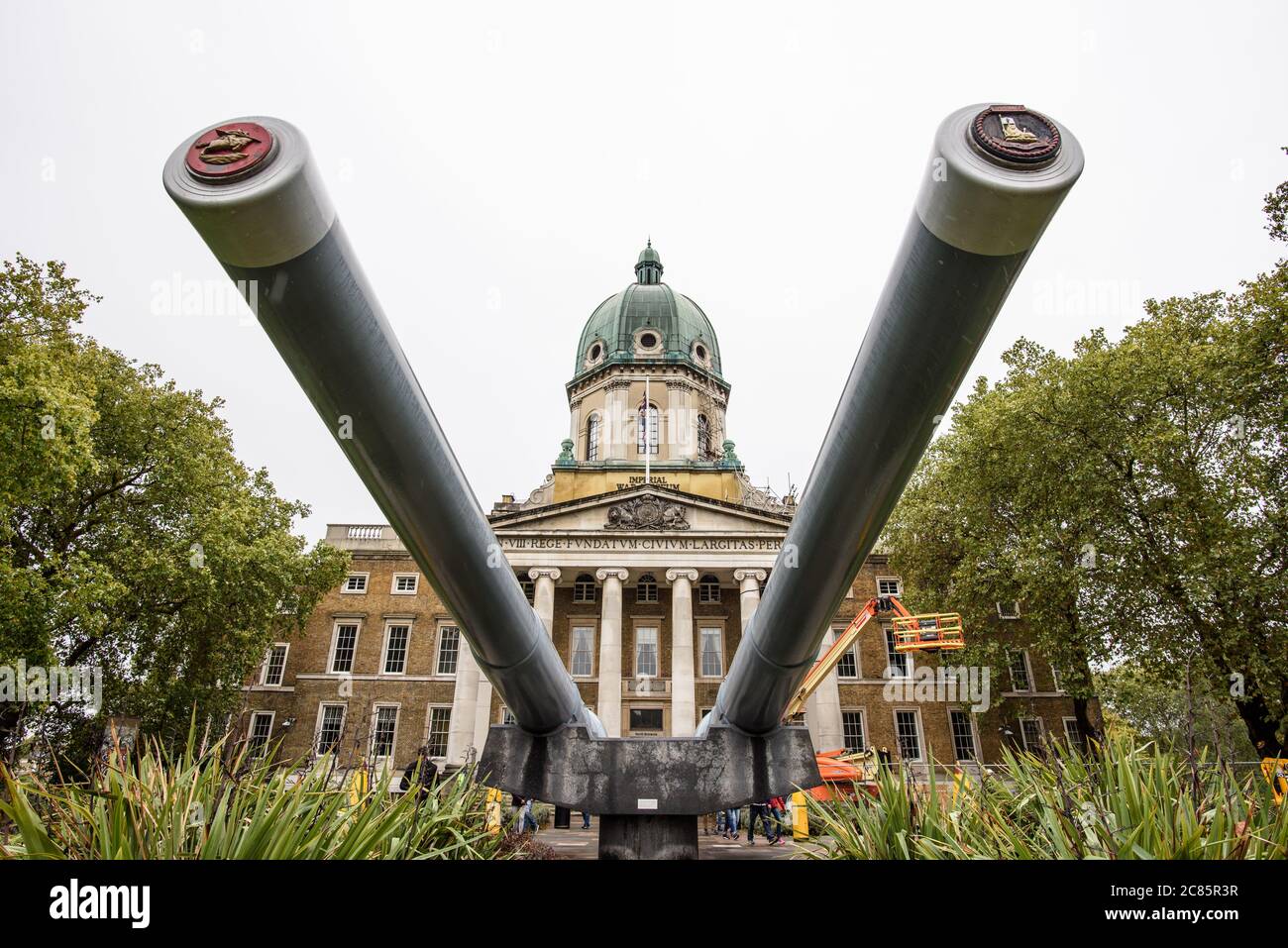 Museo della Guerra Imperiale Cannoni Navali Londra | LONDRA, Regno Unito — I cannoni navali da 15 pollici all’ingresso del Museo della Guerra Imperiale di Londra, provenienti dalle corazzate HMS Ramillies e HMS Resolution, sono qui visti da una prospettiva che enfatizza la loro elevazione davanti alla facciata neoclassica del museo. Entrambe le navi erano attive nella Royal Navy durante la Seconda Guerra Mondiale, e i cannoni riflettono la scala dell’ingegneria navale britannica nella prima metà del XX secolo. Il museo ha sede nell’ex edificio del Bethlem Royal Hospital a Lambeth dal 1936. Insieme, i cannoni e l’edificio Foto Stock