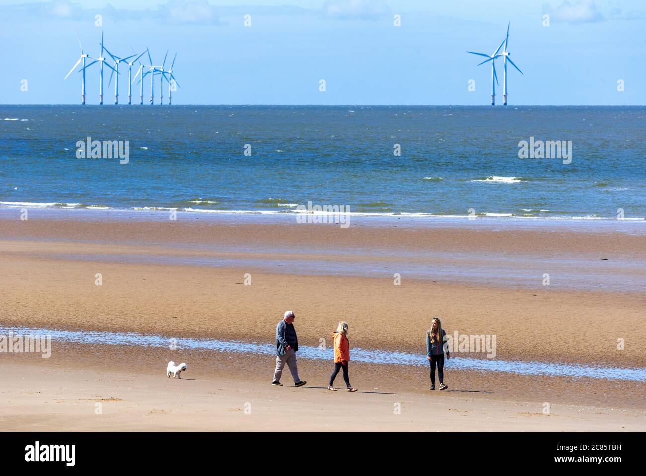 Persone che passeggiano sulla spiaggia di New Brighton sul Wirral sotto il sole. Foto Stock
