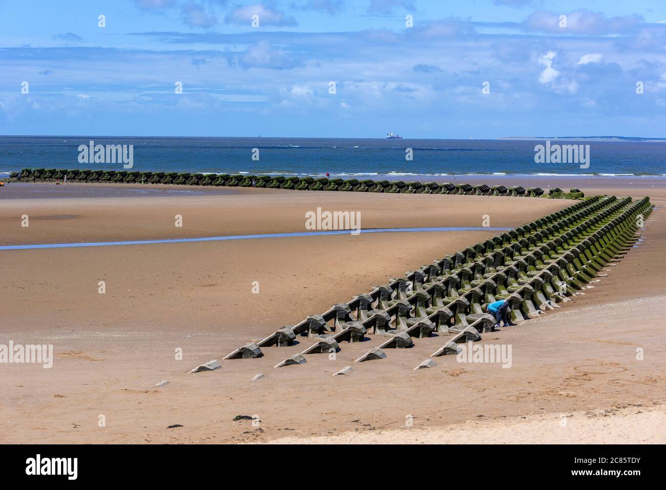New Brighton spiaggia sul Wirral al sole che mostra le massicce acque di dirufimento in cemento difese del mare. Foto Stock