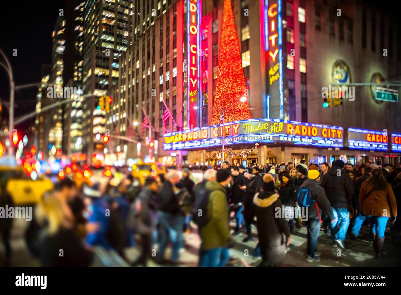 Una folla di persone attraversa la 6th Avenue di fronte al radio City Music Hall Foto Stock