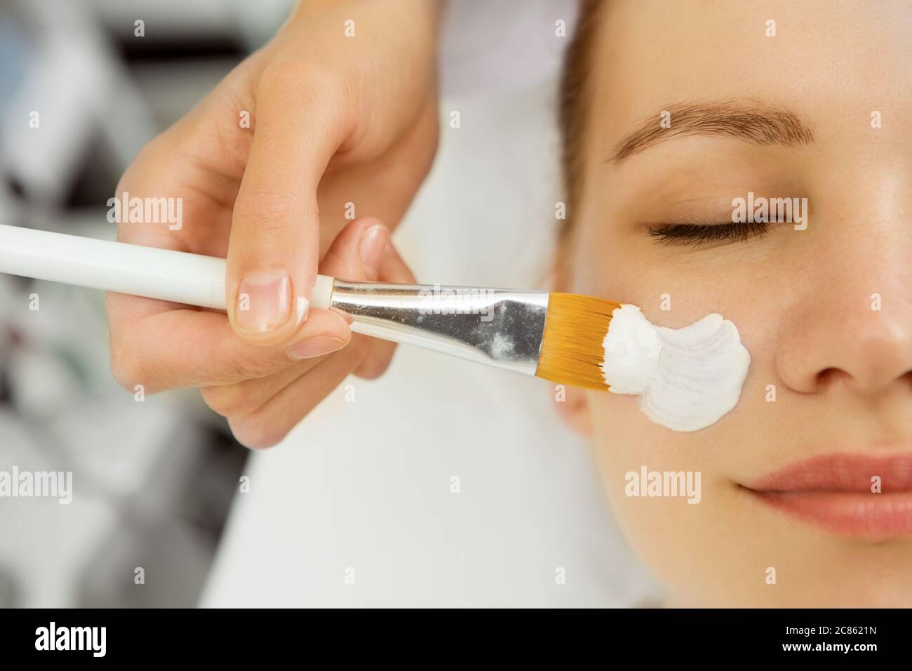 Primo piano di un estetista applicazione maschera facciale su una giovane donna viso cliente servizio terapia terapia terapeuta dermatologia cosmetologia refres Foto Stock