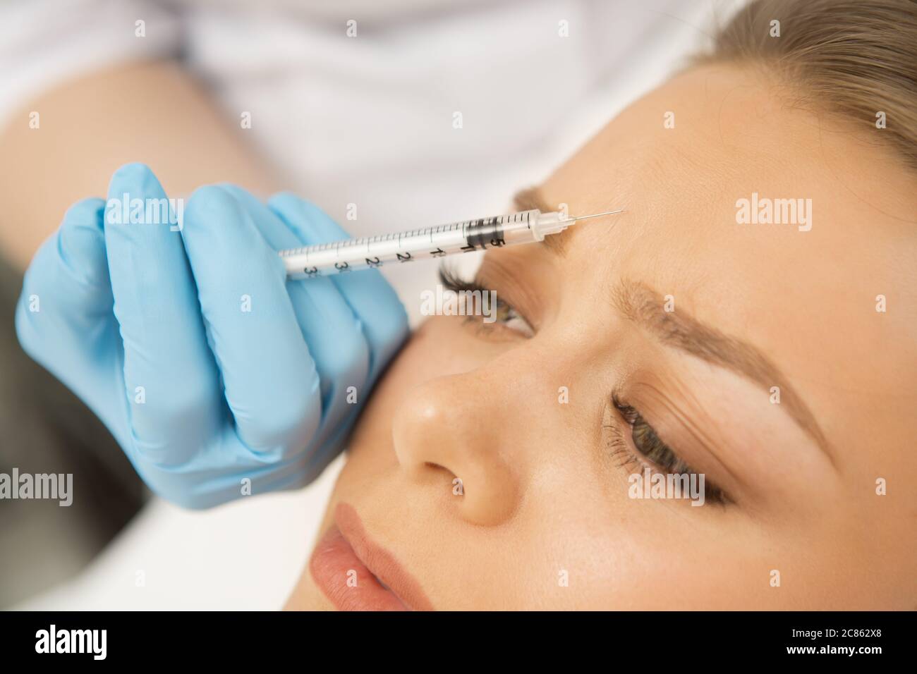 Primo piano di un cosmetologo professionista che fa l'iniezione di botox di fronte al suo cliente femminile. Bella donna che ottiene trattamento viso al clin Foto Stock