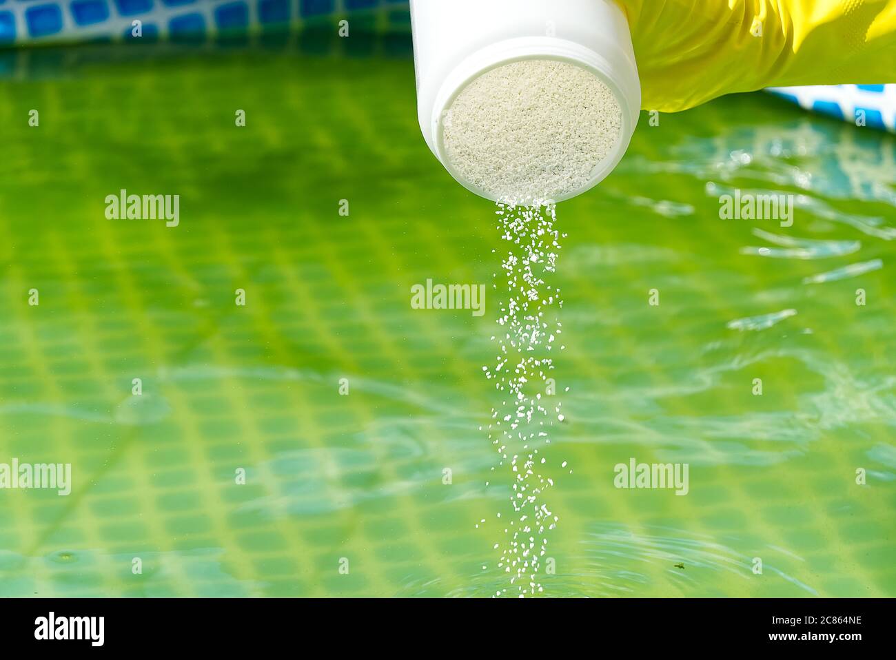 aggiunta di polvere di cloro per la piscina per rimuovere le alghe e disinfettare l'acqua. concetto gonfiabile di cura piscina. Foto Stock