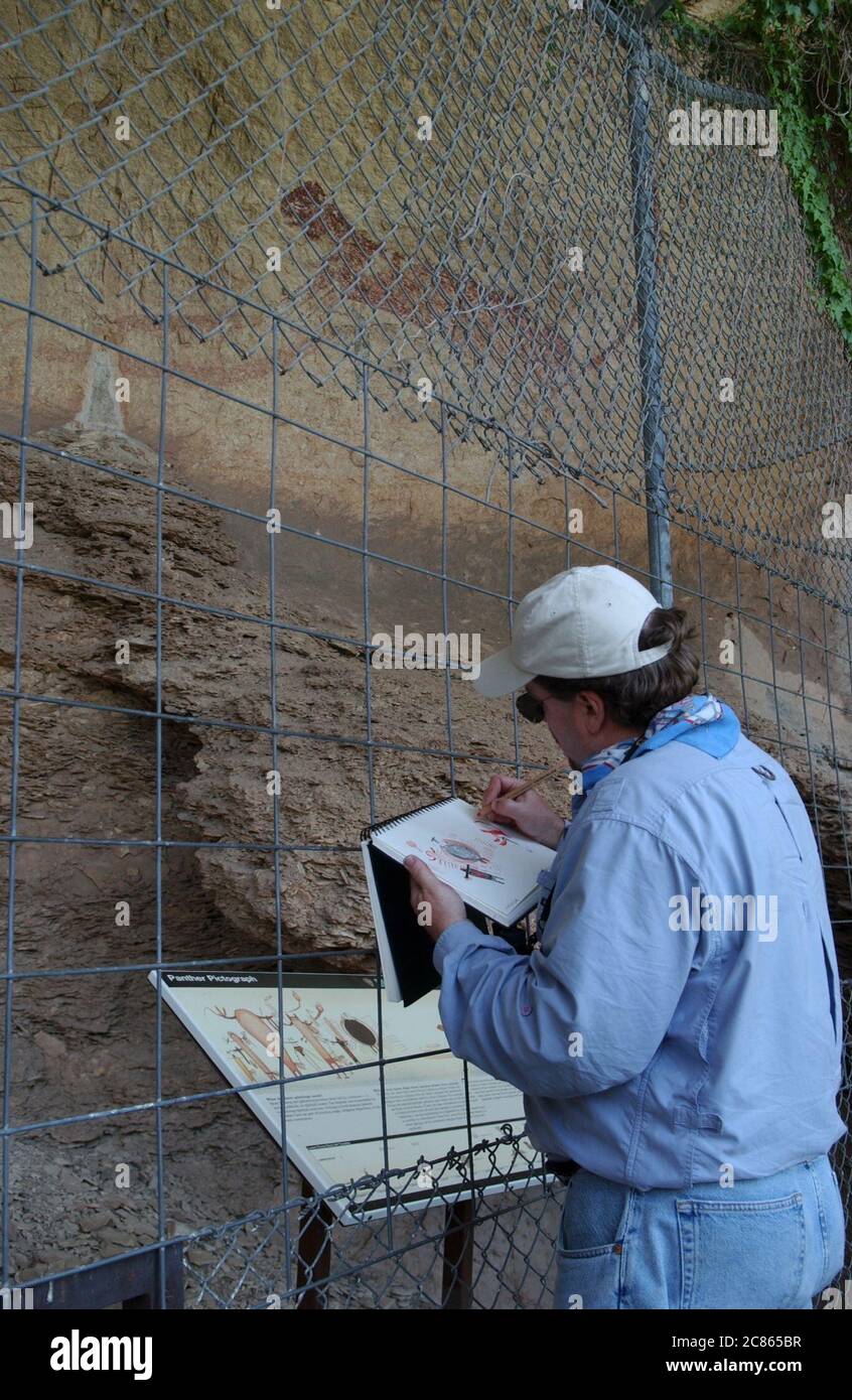 Val Verde County, Texas USA, ottobre 2004: Tourist realizza un disegno di arte rupestre nativa americana in una grotta lungo il fiume Rio grande nel Texas sud-occidentale. Gli antichi disegni sono protetti da recinzioni per proteggerli da atti vandalici. ©Bob Daemmrich Foto Stock