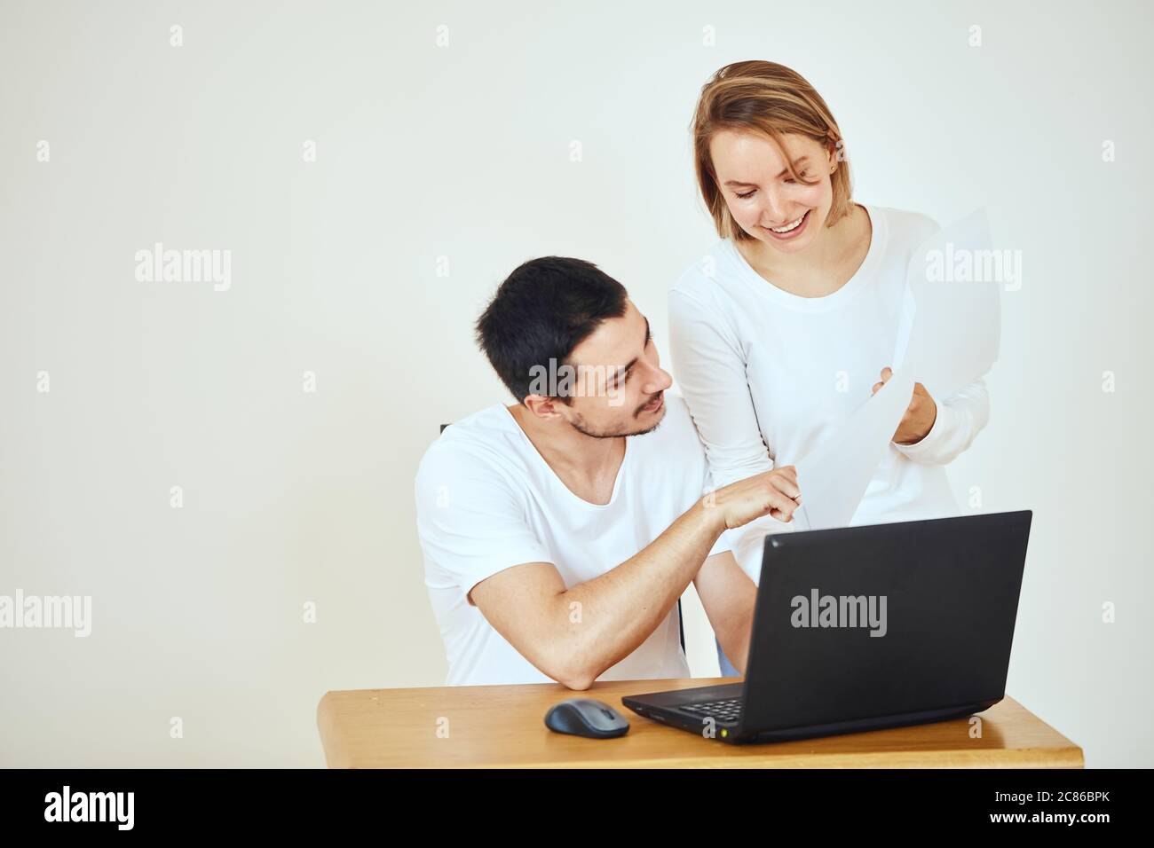 Felice giovane coppia a casa pagando le fatture con il laptop Foto Stock