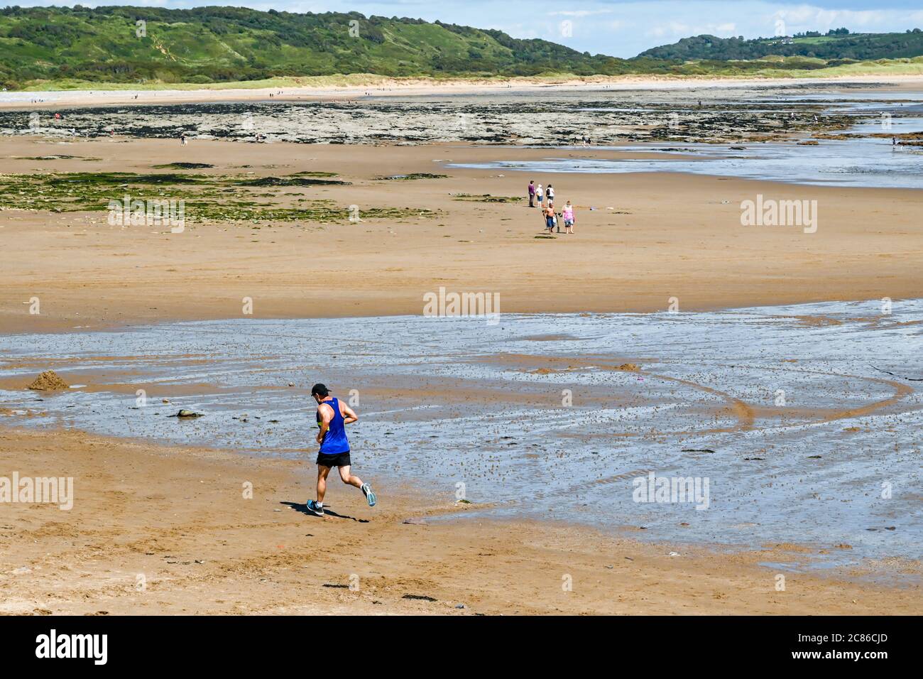 Newton Bay, Porthcawl, Galles - Luglio 2020: Persona che corre su Newton Beach a bassa marea. Foto Stock