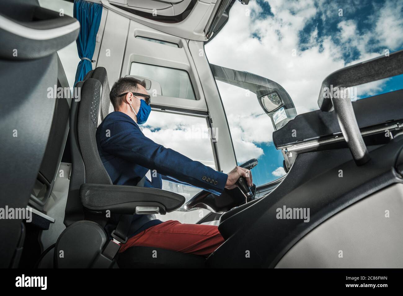 Autista del bus navetta all'interno del veicolo moderno. Viaggi lungo viaggio su strada. Driver caucasico. Foto Stock