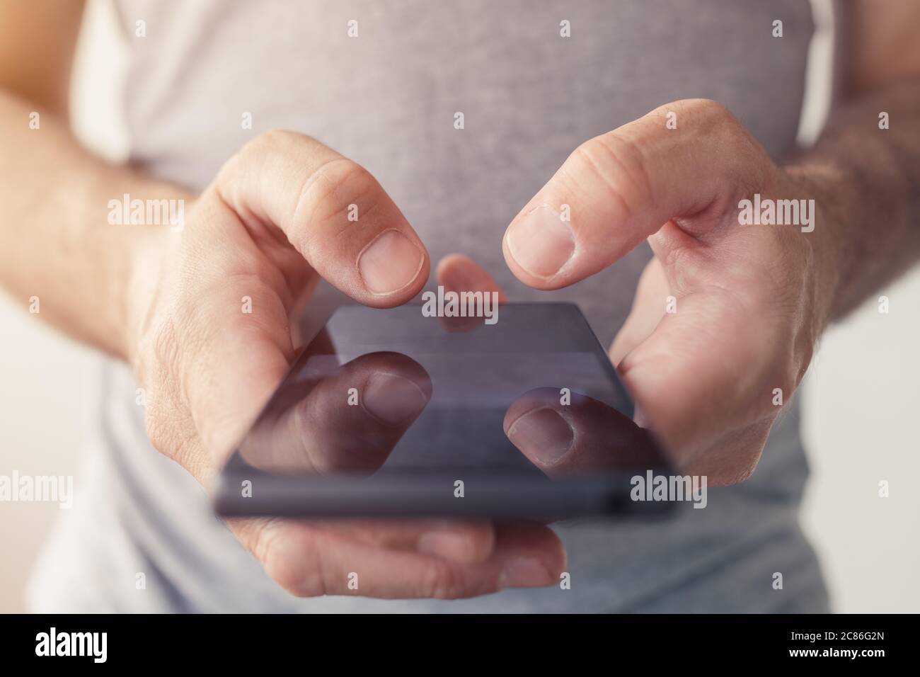 Primo piano di mani maschili che digitano messaggi di testo sullo smartphone, messa a fuoco selettiva Foto Stock