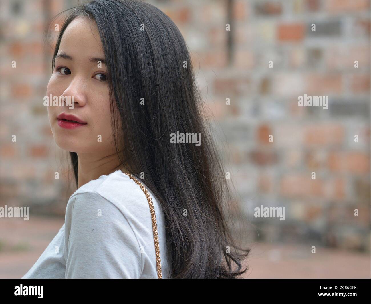 Bella ragazza vietnamita si allontana e dà un ultimo sguardo sulla sua spalla. Foto Stock