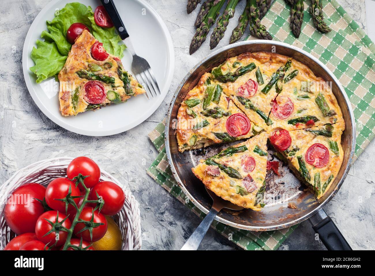 Frittata fatta di uova, asparagi e pomodori ciliegini su una padella. Cucina italiana Foto Stock