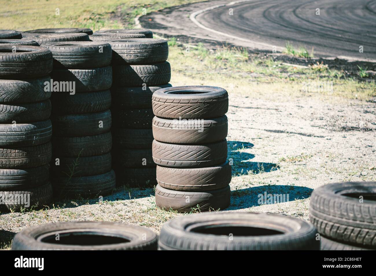 Molti vecchi pneumatici usati per auto accatastati l'uno sull'altro nel complesso sportivo dell'automobile. Discarica industriale per la lavorazione di pneumatici e gomma usati Foto Stock