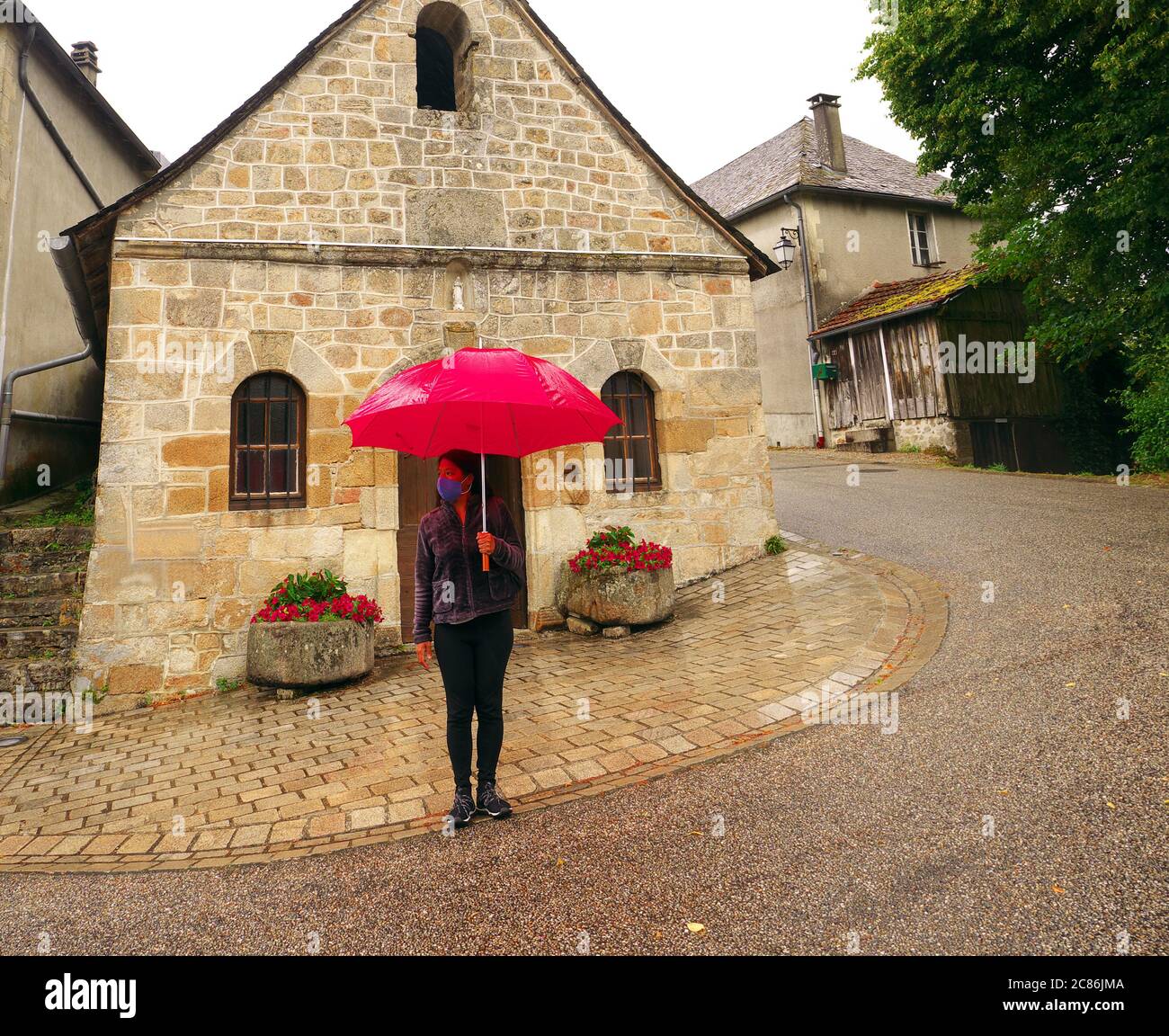 Foto scattata in un piccolo villaggio in Francia durante il tempo piovoso. I turisti si proteggono dal covid-19 anche durante le vacanze estive Foto Stock