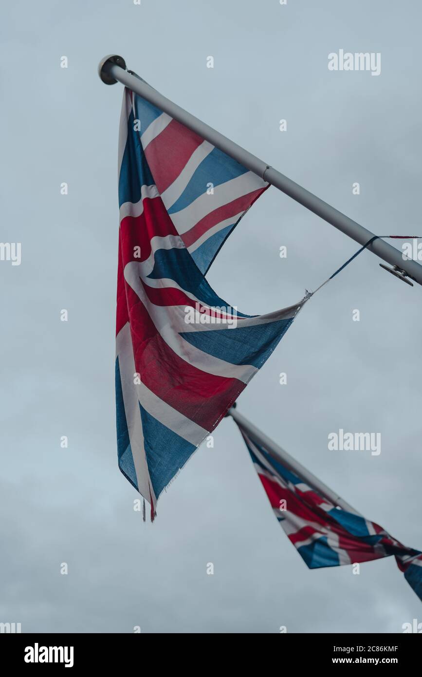 Union Jack si batte su un flagpole a Stow-on-the-Wold, Cotswolds, Regno Unito, contro un cielo grigio cupo, fuoco selettivo. Foto Stock