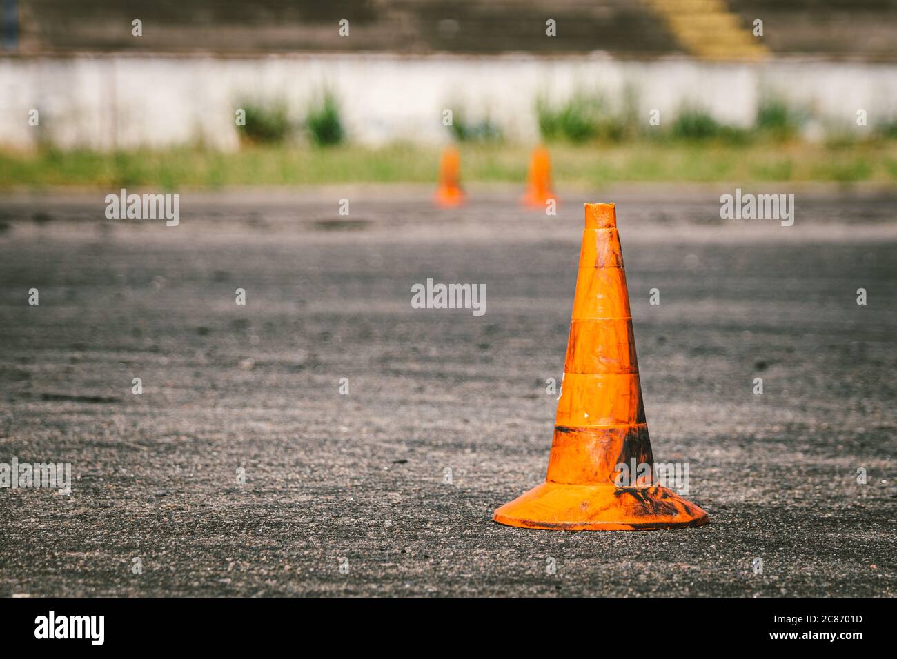 Primo piano di un vecchio cono di traffico arancione sporco presso il sito per l'addestramento alla guida o la scuola di auto. Segni rossi di plastica all'autodromo, guida estrema Foto Stock