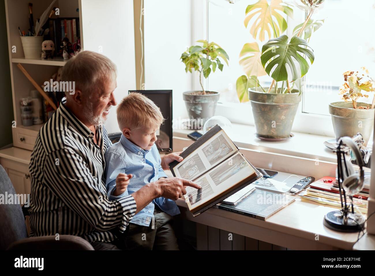Senior uomo e bambino di detenzione e guardando album di foto di famiglia in soggiorno Foto Stock