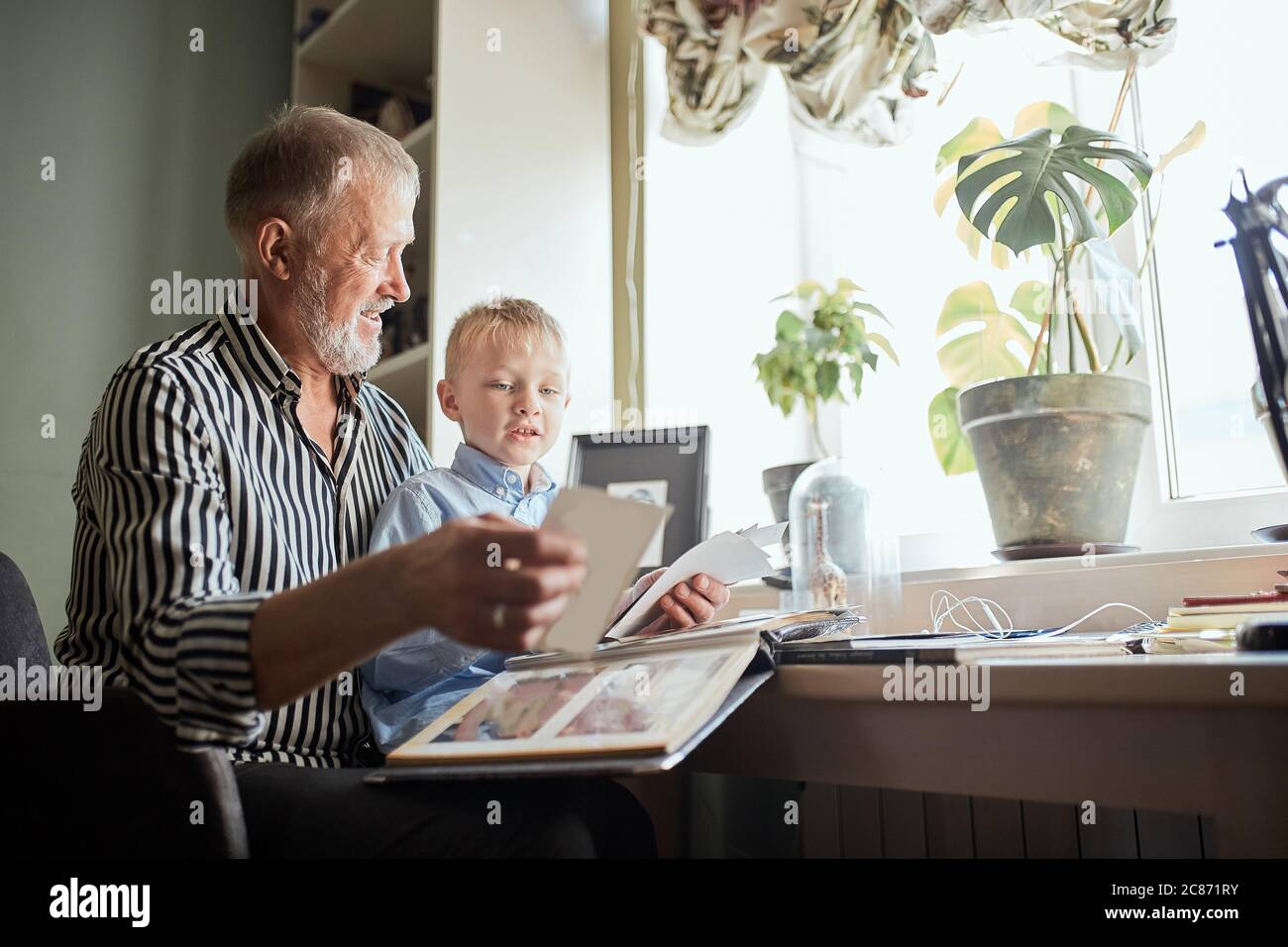 Nonno e nipote sul divano di casa. Il nonno e i bambini a guardare le vecchie foto in un album Foto Stock