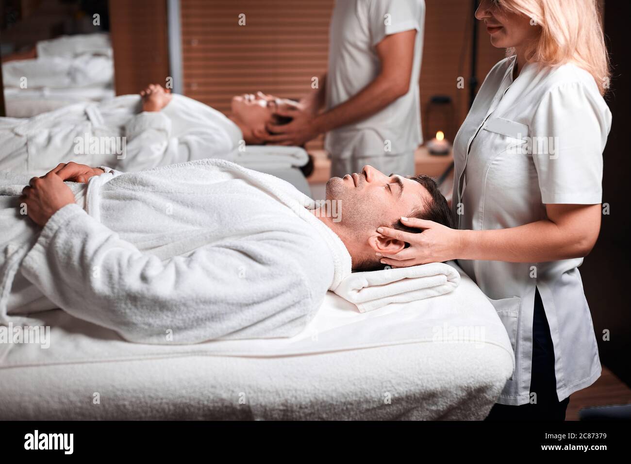 Immagine ravvicinata di un caucasian giovane uomo ricevere il massaggio del viso presso il centro termale. Esperta massaggiatrice allentando la tensione del client maschio facendo therap Foto Stock