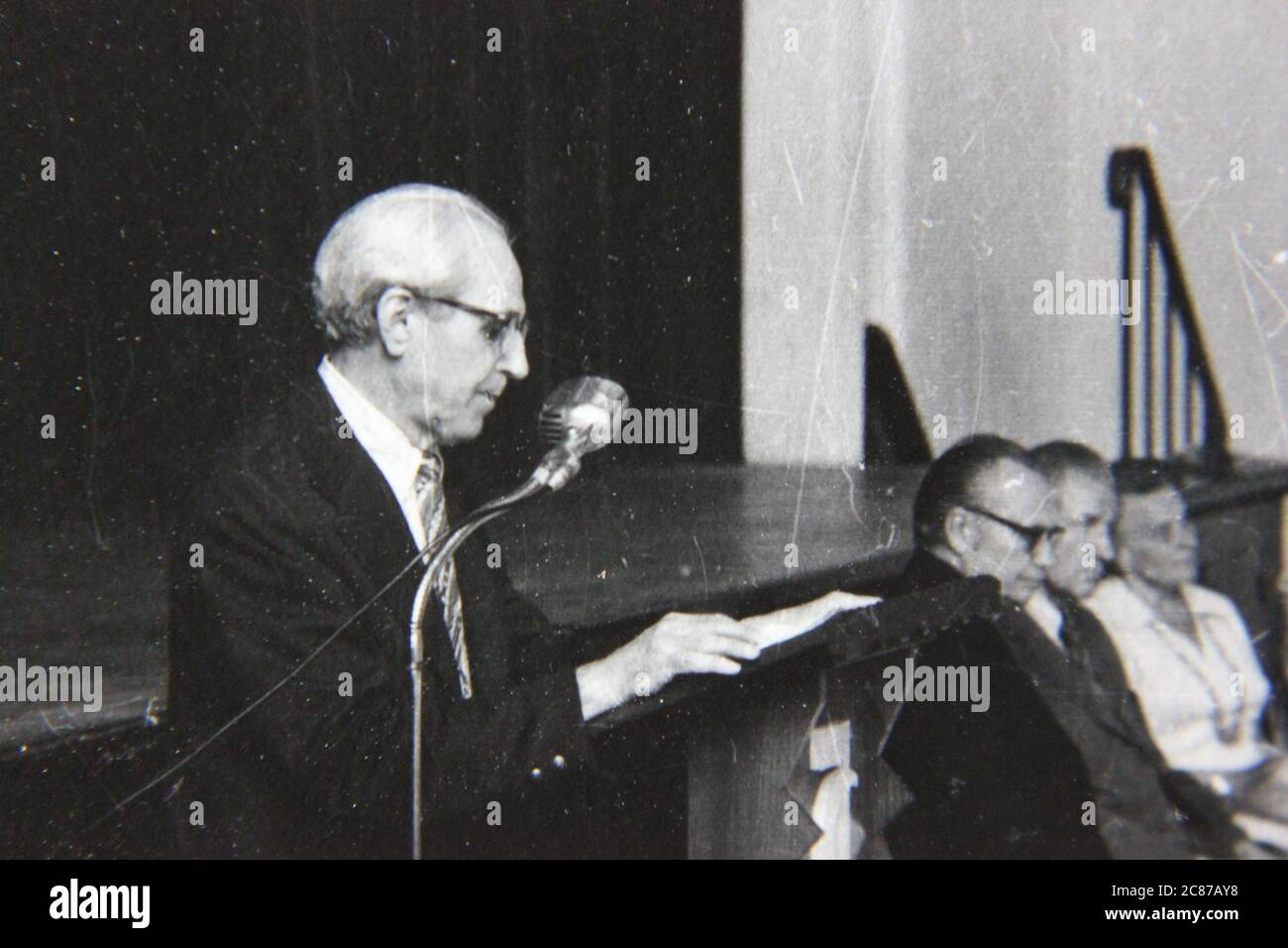 Bella fotografia in bianco e nero degli anni '70 di un oratore pubblico che fa annunci sul podio. Foto Stock