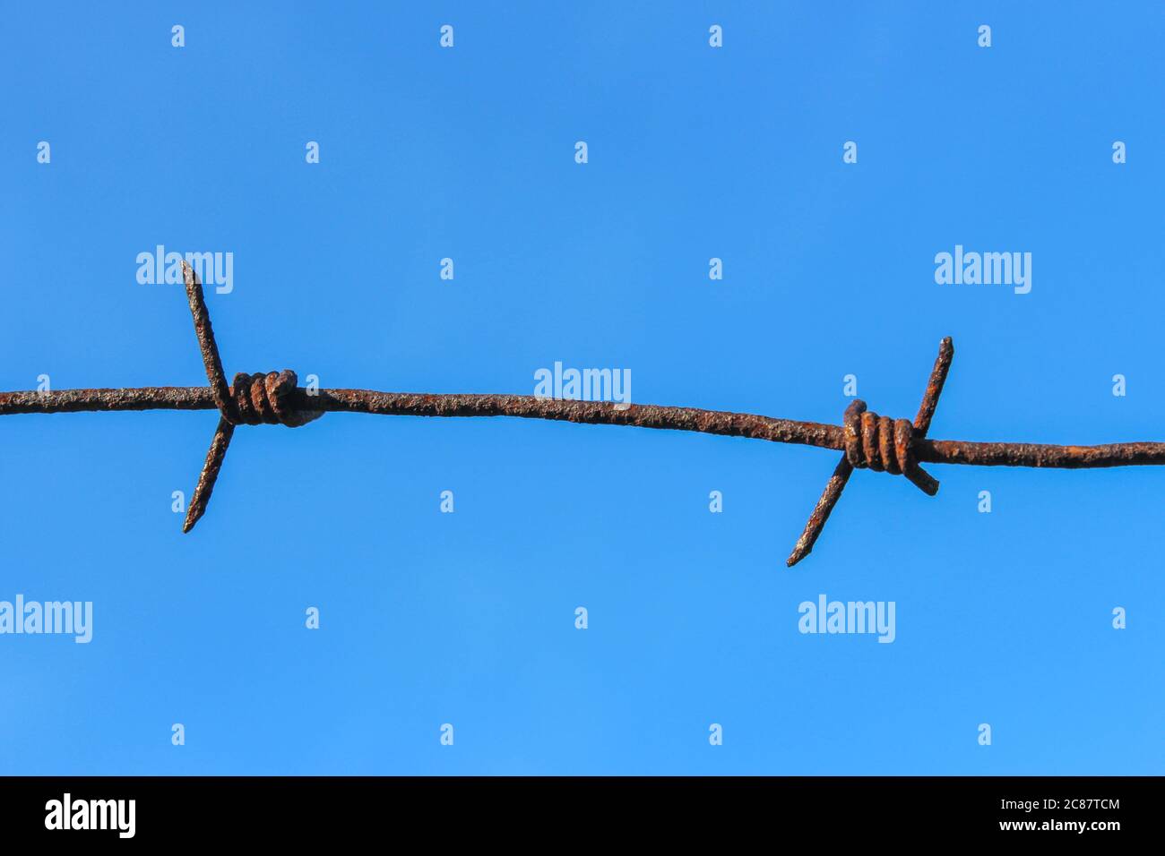 Frammento di vecchio filo spinato arrugginito su sfondo blu del cielo Foto Stock