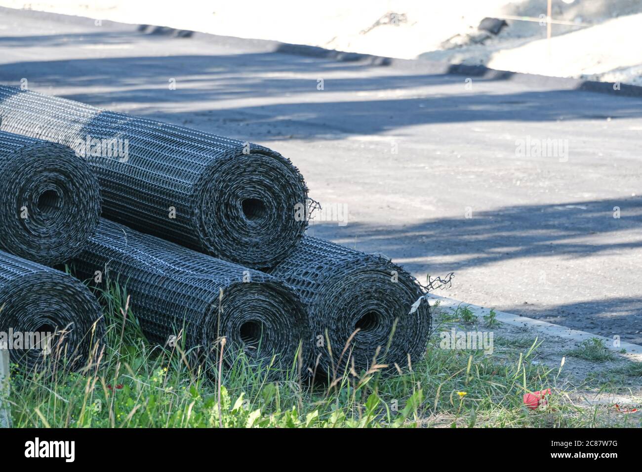 Rotoli di rete di filo recinzione a bordo strada in un cantiere Foto Stock