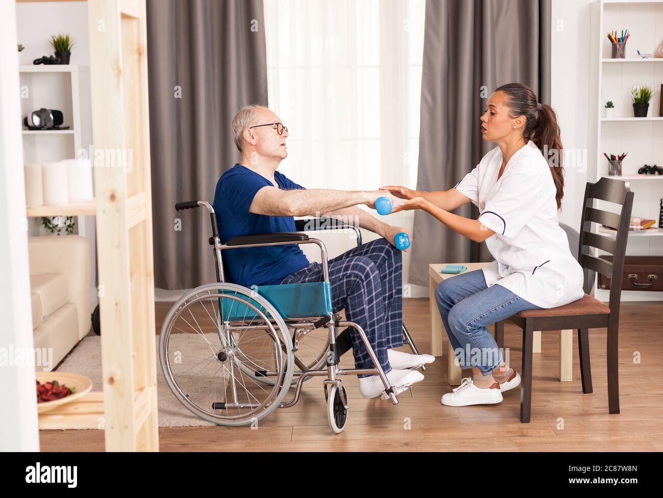 Anziano disabile durante la fisioterapia parlando con il medico del suo dolore. Disabili anziani disabili con lavoratore sociale in recupero terapia di supporto fisioterapia sistema sanitario di cura casa di riposo Foto Stock