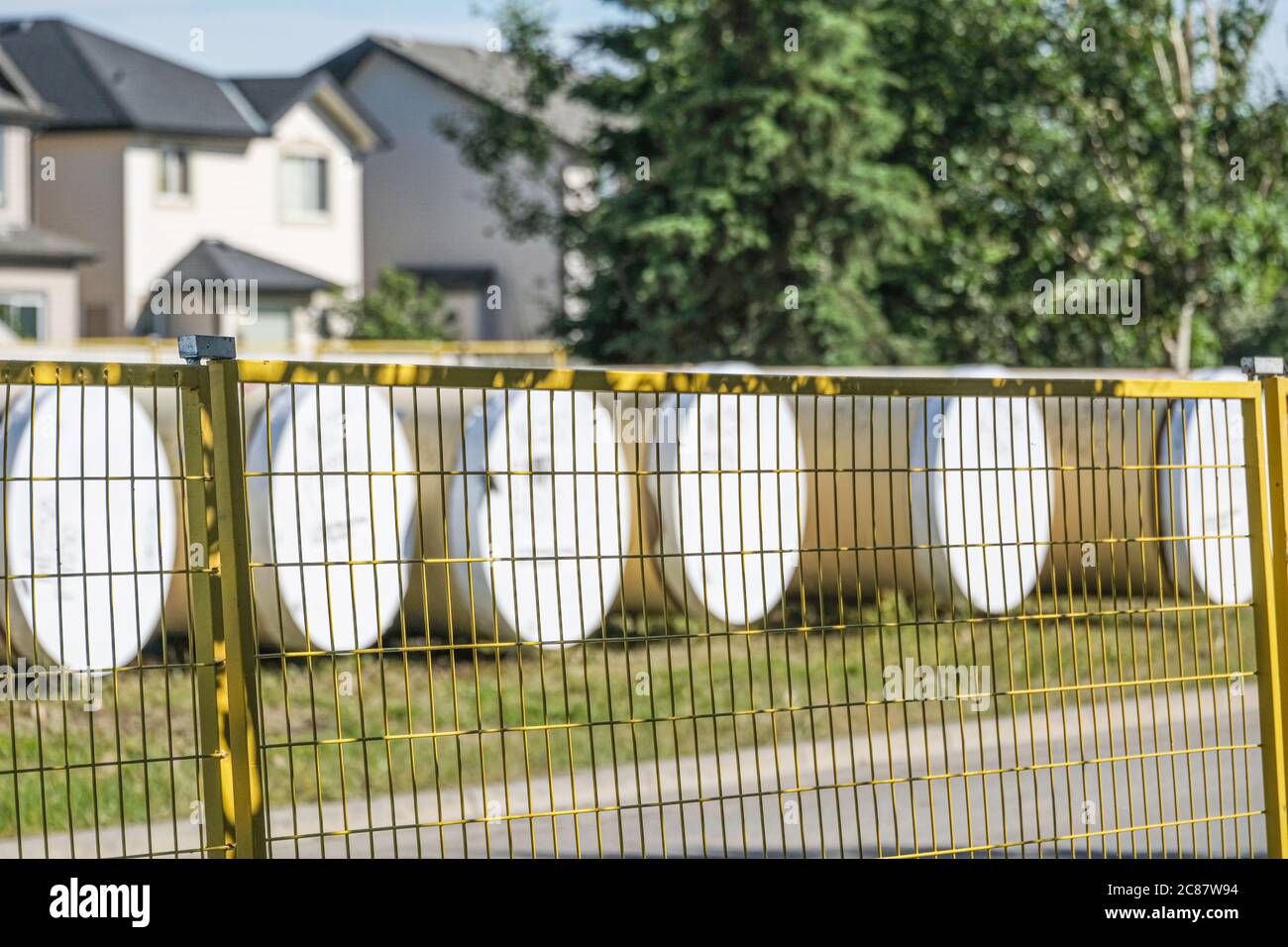 Tubi dell'acqua dietro la recinzione gialla temporanea in un cantiere Foto Stock