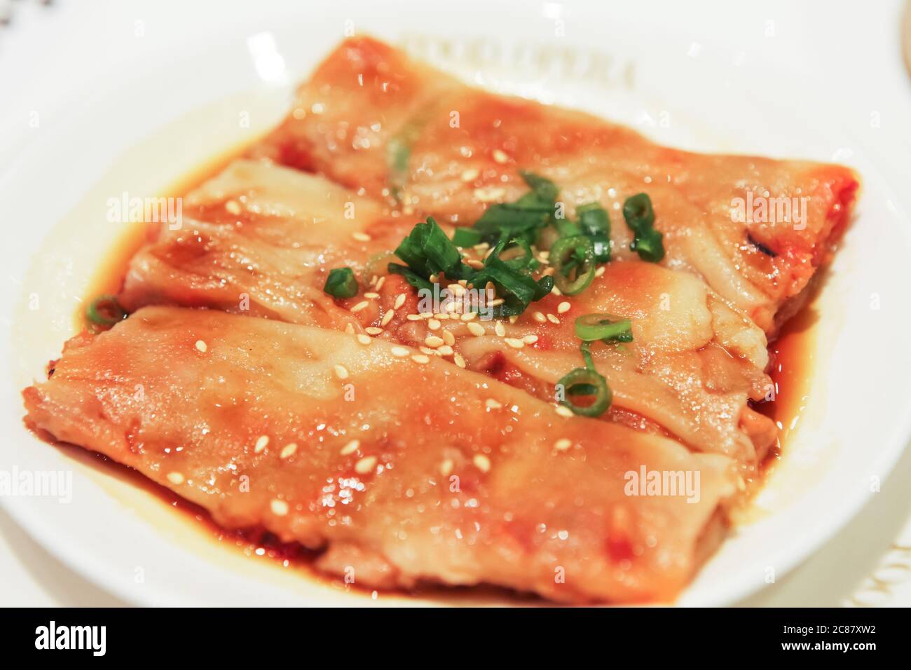 Primo piano vista del divertimento di Chee Cheong liscio o rotolo di noodle di riso servito su un piatto bianco, cospargere con cipolle primaverili e semi di sesamo, Singapore Foto Stock