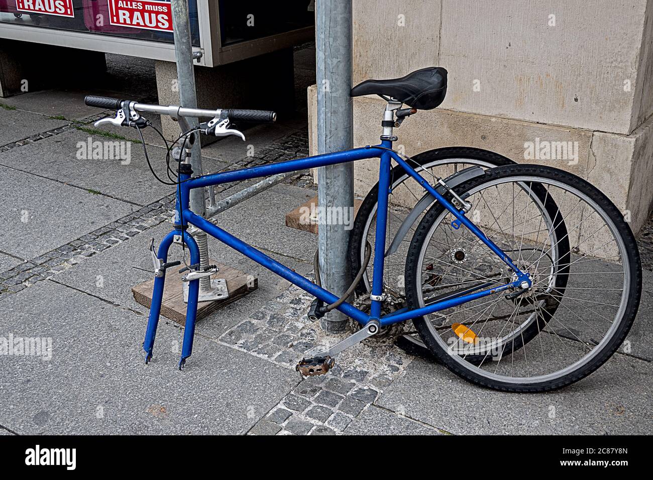 bici blu con pneumatico rimosso incatenato ad una grondaia Foto Stock