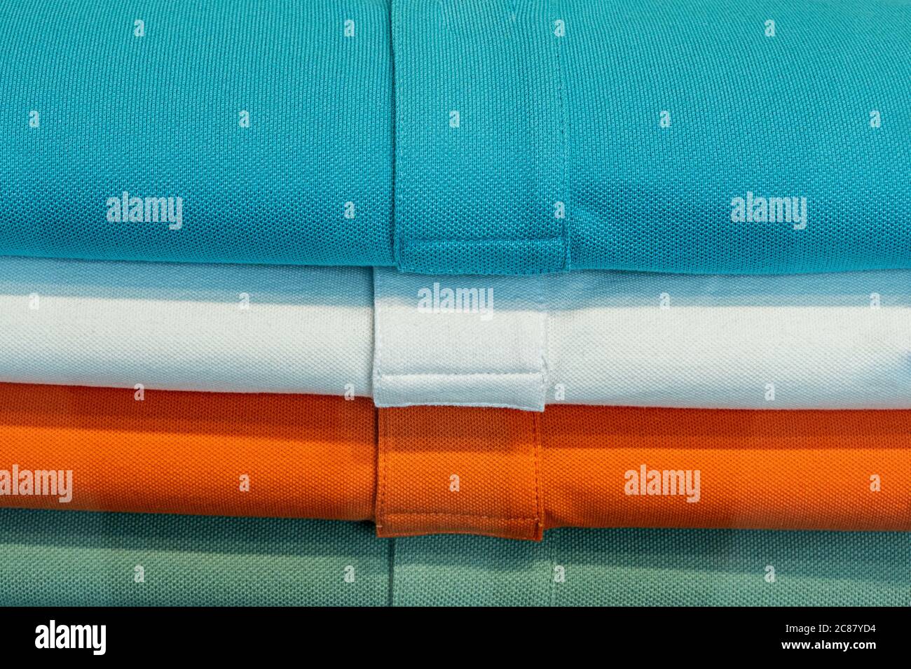 camicie di colore blu, bianco, arancione e verde in un mucchio Foto Stock