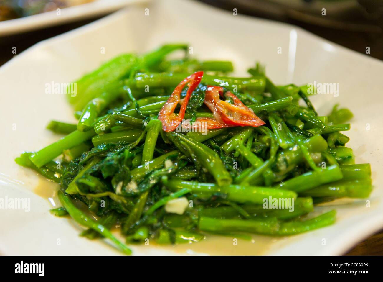 Verdure fritte con peperoncino rosso sulla parte superiore, un piatto di ordine comune quando si mangia al ristorante/stalla Zi Char a Singapore o Hong Kong. Foto Stock