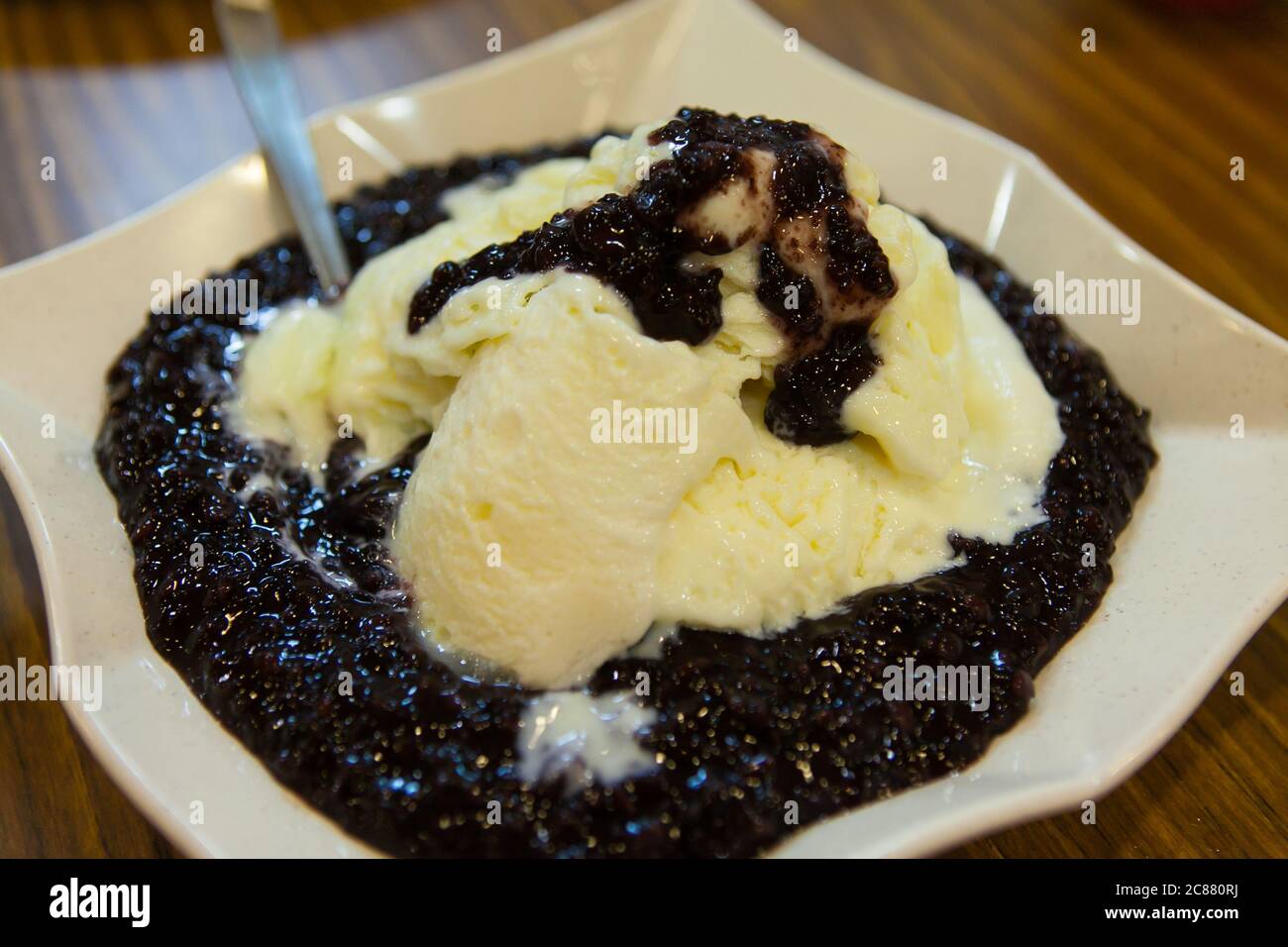 Dessert di riso glutinoso nero servire con gelato alla vaniglia in un piatto. Foto Stock
