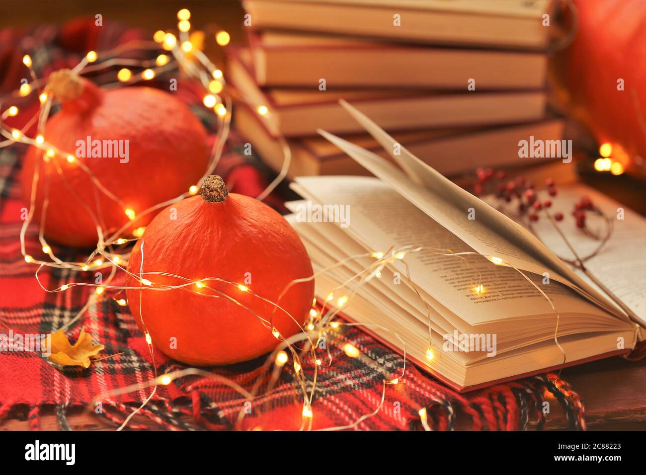 Autunno books.Autumn reading.Stack accogliente di libri, zucche hokkaido rosso con ghiaia, scacchi primo piano sciarpa Foto Stock