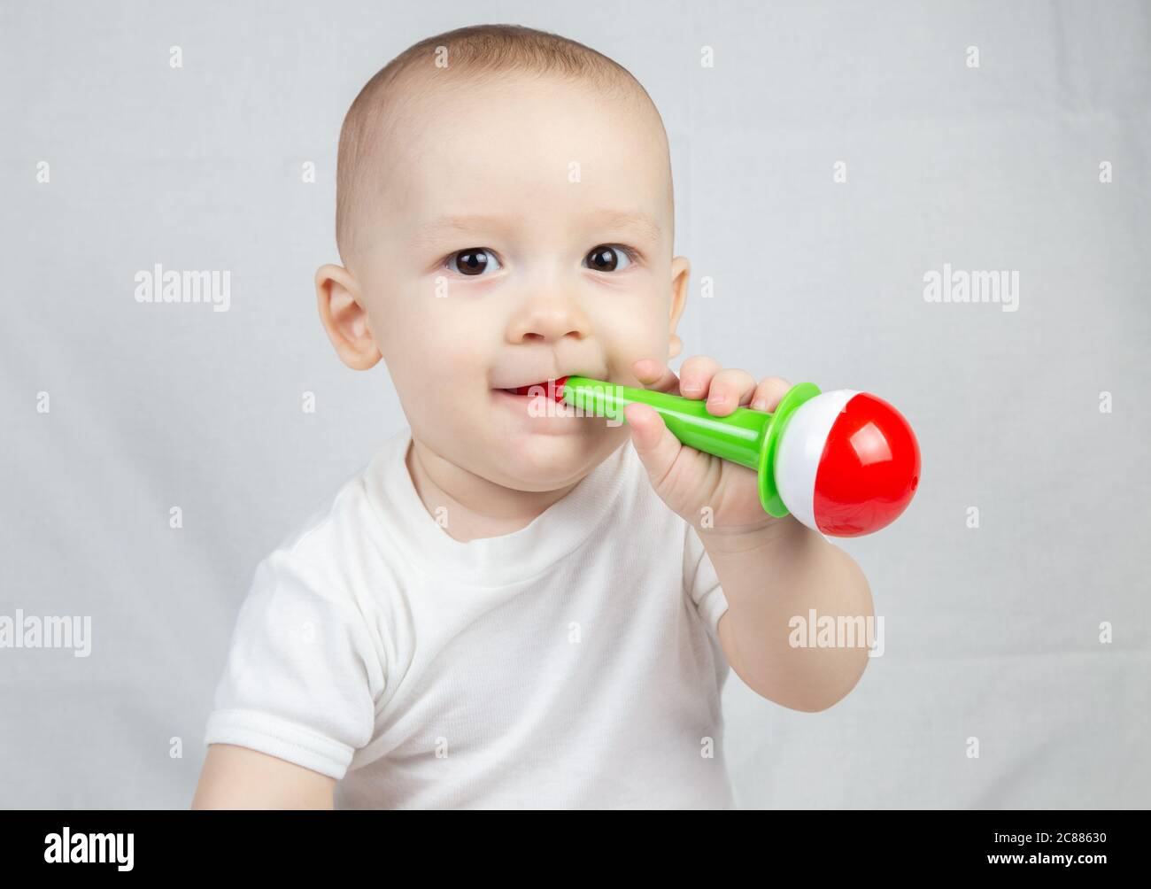 Foto di un bambino di otto mesi con sonaglino in bocca Foto Stock