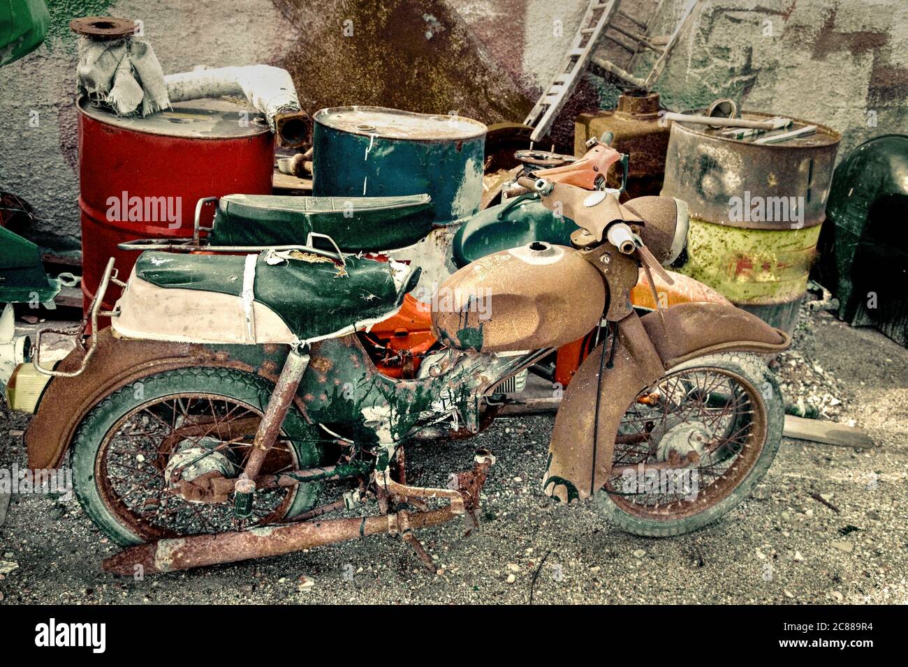 Moto spazzatura abbandonate. Moto vecchio stile retrò diss-utilizzato con tamburi ad olio e altra spazzatura in discarica. Immagine stock Foto Stock