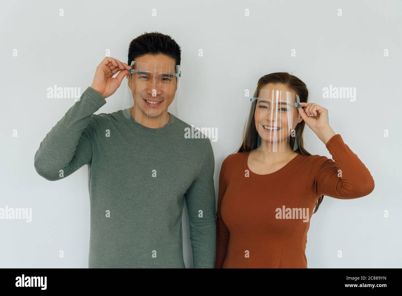 Allegro uomo e donna cinese sorridente e indossare indumenti protettivi personali rivestimenti per il viso Foto Stock